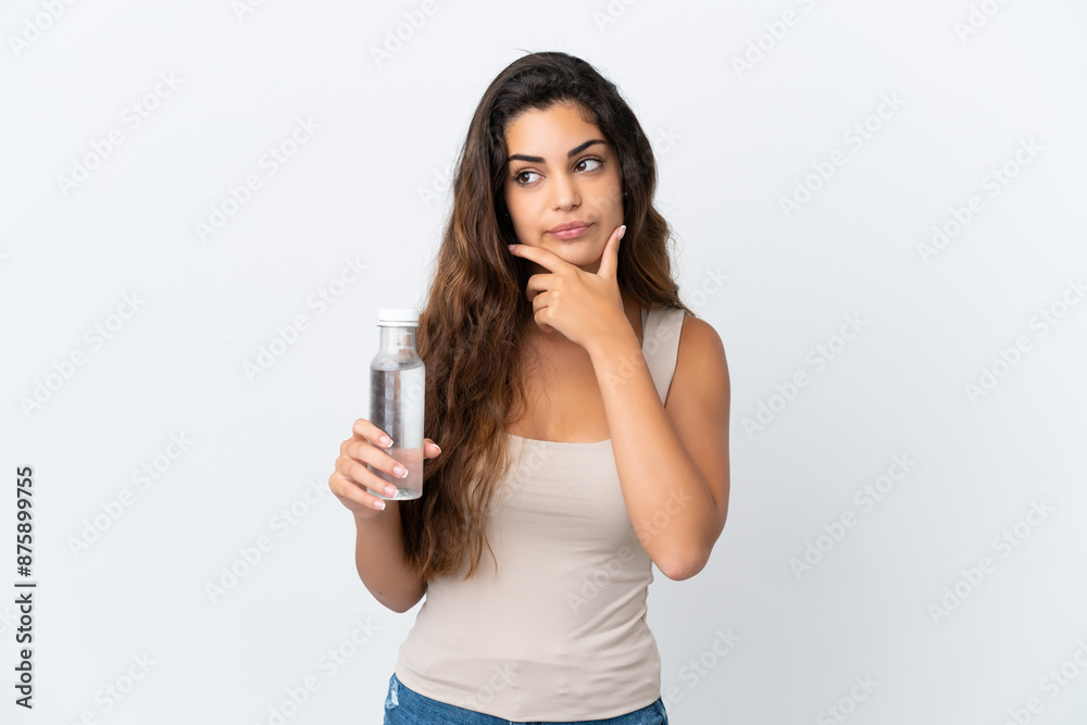 Young caucasian woman with a bottle of water isolated on white background having doubts Young caucasian woman with a bottle of water isolated on white background having doubts