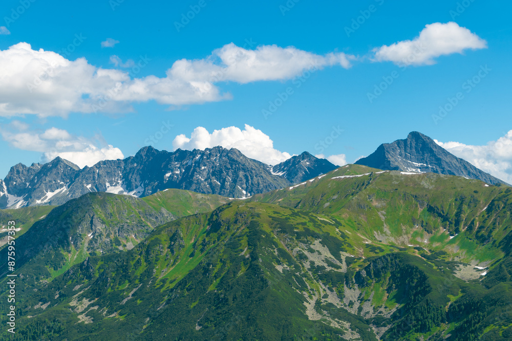 Fototapeta premium Beautiful mountain landscape in summer. Green grass, high rocks, blue sky and white clouds. Natural background. Tatra Mountains