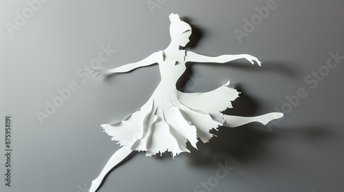 Paper cutout silhouette of a ballet dancer in motion, featuring graceful, delicate design and intricate details on a gray background.