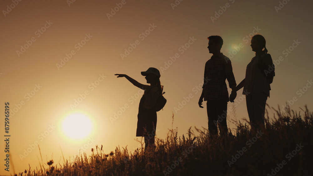 Silhouettes of a happy family, together they meet the dawn in a picturesque place Silhouettes of a happy family, together they meet the dawn in a picturesque place
