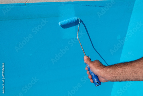 Photos Pintor habilidoso aplica cores brilhantes no chão e paredes da piscina com um to