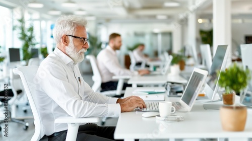 Senior Businessman Typing on Laptop in Modern Office Environment