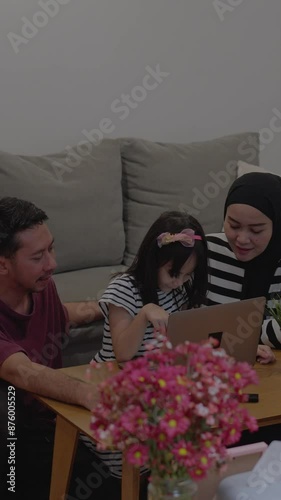 Asian Parents With Daughter Doing Homework Using Laptop At Home. Parenting Responsibilities.