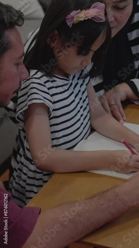 Asian Muslim Parents Is Teaching Daughter Homework At Home. Happy Family Lifestyle.