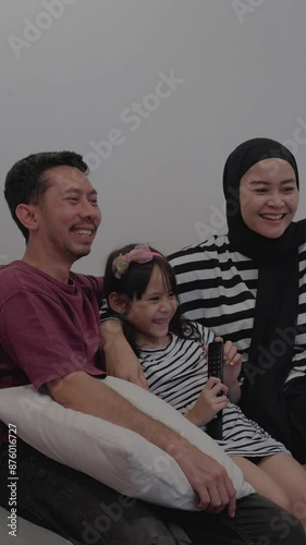 Asian Family Sitting On A Couch And Watching A Movie Together At Home 