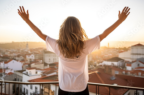 A woman welcoming the sunrise with open arms on a balcony overlooking a cityscape