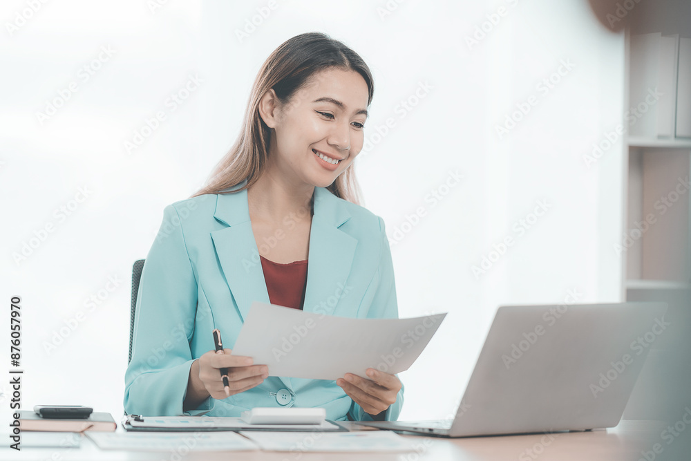 Asian businesswoman sitting at table and calculating financial graphs showing investment results Junior Accountants calculate taxes, expenses, and finances with results in easy-to-read graphs. Asian businesswoman sitting at table and calculating financial graphs showing investment results Junior Accountants calculate taxes, expenses, and finances with results in easy-to-read graphs.