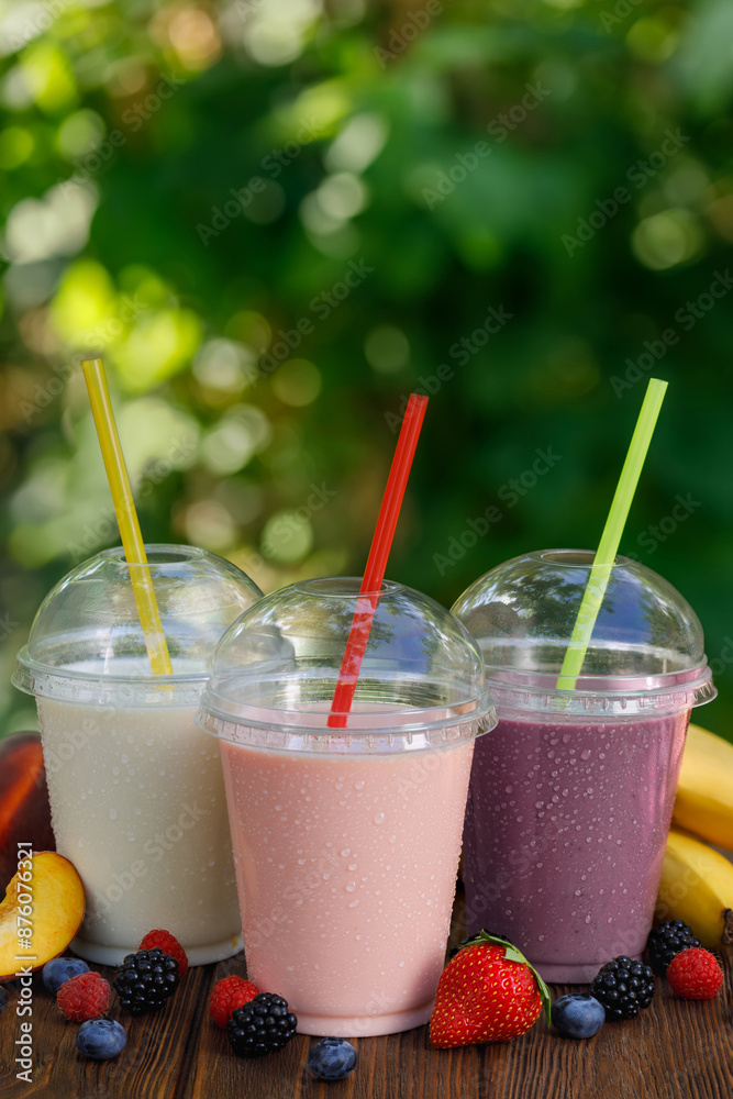 set of different flavor milkshakes or smoothie in disposable plastic glasses on wooden table outdoors set of different flavor milkshakes or smoothie in disposable plastic glasses on wooden table outdoors
