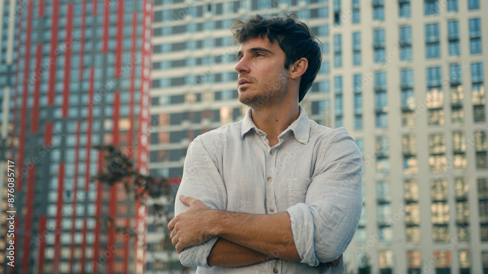 Portrait of handsome young business man 30s millennial confident guy looking at camera crossed hands posing on street successful male model in city living urban lifestyle office buildings background Portrait of handsome young business man 30s millennial confident guy looking at camera crossed hands posing on street successful male model in city living urban lifestyle office buildings background