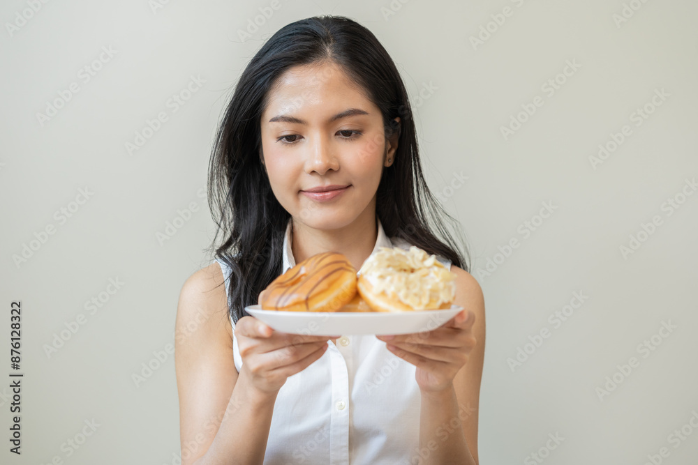 Portrait of happy smile asian young woman, girl temptation food, holding donut plate, enjoy eating sugar glazed doughnut delicious dessert sweet, snack tasty. Eat fast food, junk food meal getting fat