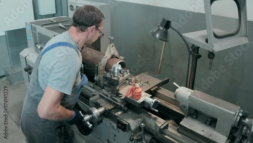 A machinist operates a lathe machine on a large metal pipe inside an industrial workshop, demonstrating the essential processes and precision needed for mechanical fabrication and component shaping.