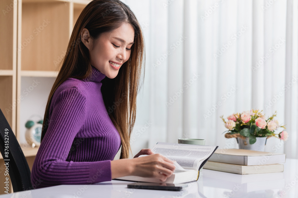 Beautiful smiling young woman in sweater reads a book on table in the living room, relax at home. Beautiful smiling young woman in sweater reads a book on table in the living room, relax at home.