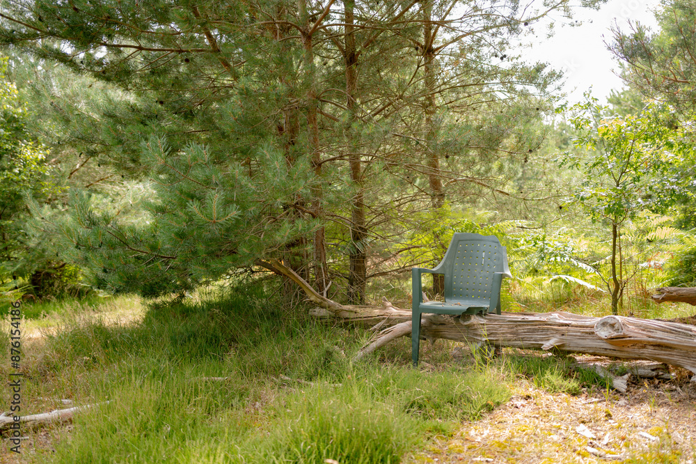 Old, plastic three legged chair seen perched on a fallen tree in a wilderness area. Part of a campsite used by off the grid peoples. Old, plastic three legged chair seen perched on a fallen tree in a wilderness area. Part of a campsite used by off the grid peoples.