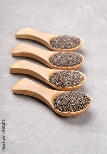 Four wooden spoons full of chia seeds close-up on concrete background