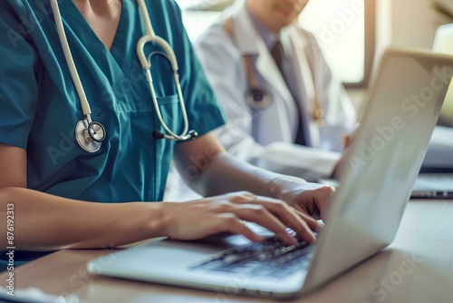 Nurse and doctor working on laptop in hospital office, white male nurse wearing uniform with stethoscope standing near desk talking to female student while using computer for medical research