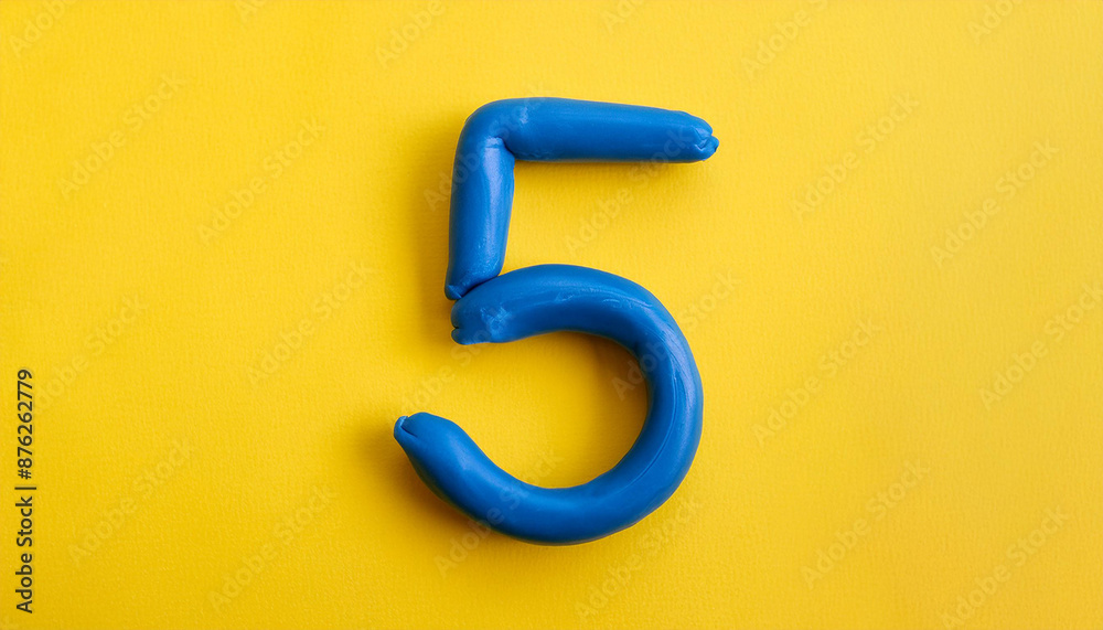 Naklejka premium Numbers 5 made of blue plasticine on yellow background. Math learning, development. Flat lay