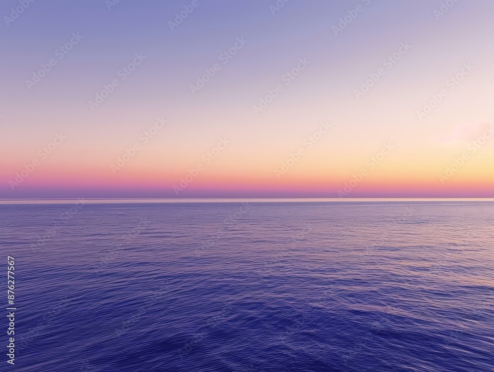 Fototapeta premium The ocean stretches out to the horizon with a calming purple hue, as the sunset paints the sky with soft pink and purple tones
