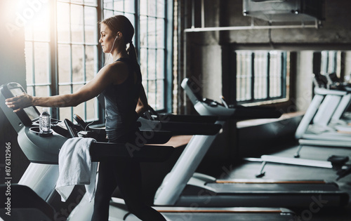 Running, fitness and woman on treadmill in gym listening to music, audio and radio for cardio workout. Sports, wellness and person with earphones for exercise, marathon training and practice for race © peopleimages.com