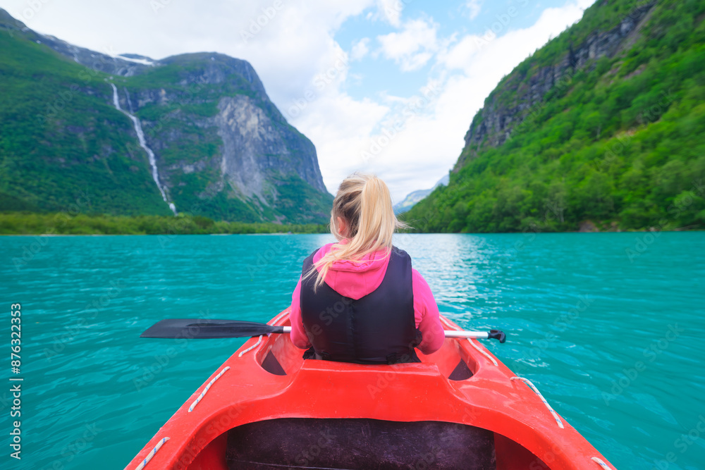 A girl sailing a canoe on a Norwegian fjord. Nature in fjords. Traveling by kayak on a Norwegian fjord. Scandinavia. Vacation and travel in summer Norway.