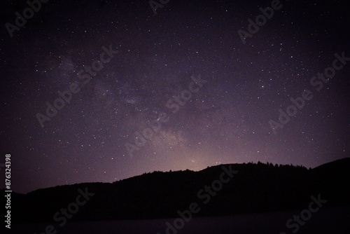 Long Exposure of the sky near the forest and lake at night time. Stars and galaxy. astro photography