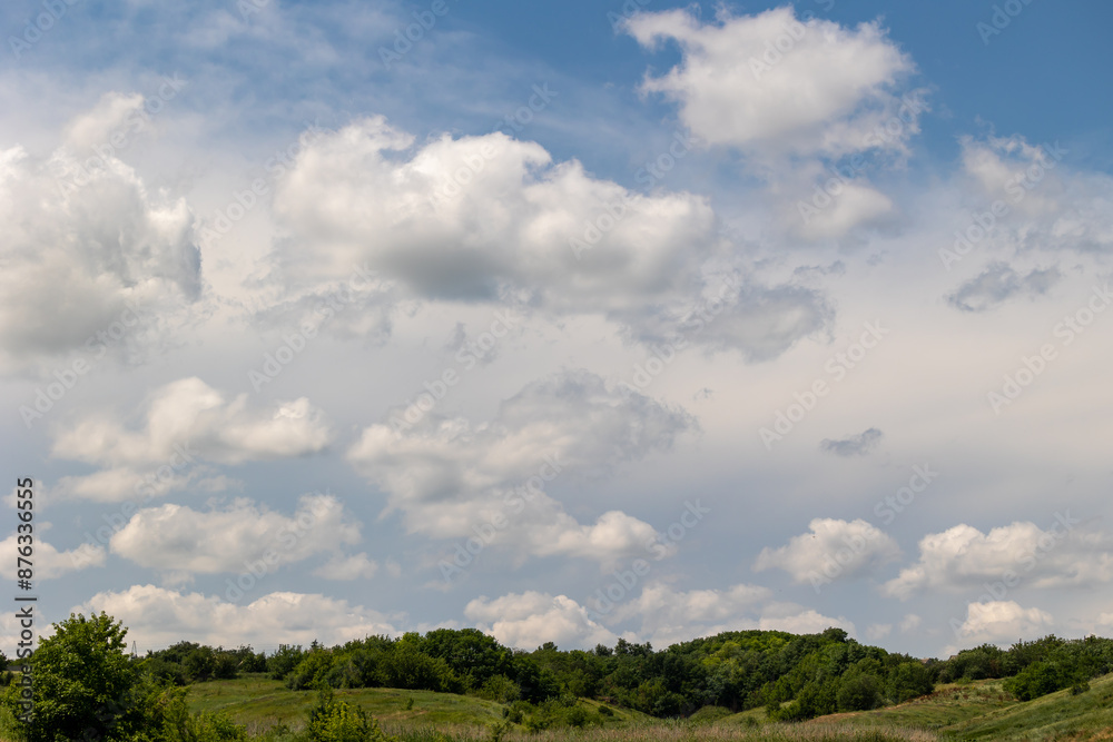 Clouds in the blue sky over a valley with hills Clouds in the blue sky over a valley with hills