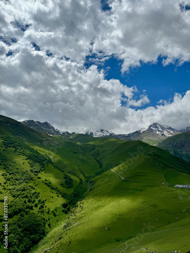 Panoramic view of the green lush peak of the Caucasus mountains with cloudy sky in Kazbegi, Georgia