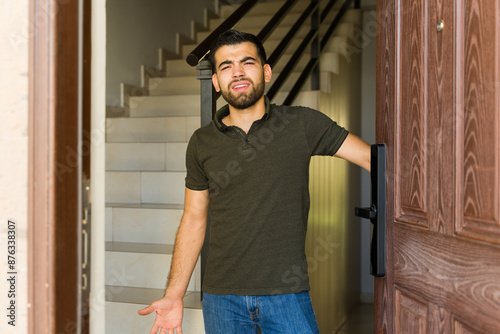 Upset man at home door, looking unhappy about people knocking on his door and disturbing his peace