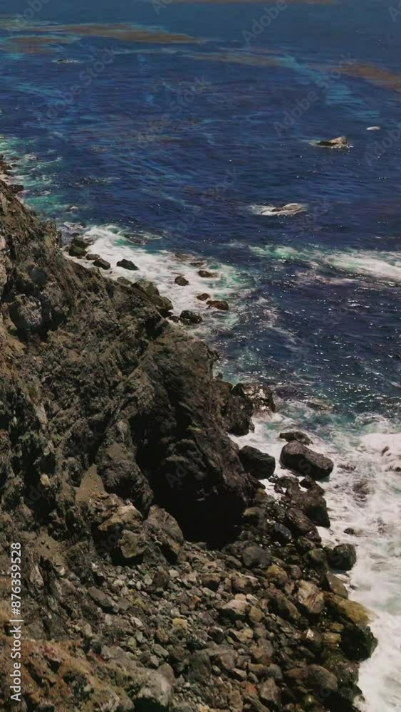 Flight over the cliff on the coastline of Pacific ocean. Some grass and moss covering the shore. Houses and roads on the top of mountains. Vertical video Flight over the cliff on the coastline of Pacific ocean. Some grass and moss covering the shore. Houses and roads on the top of mountains. Vertical video