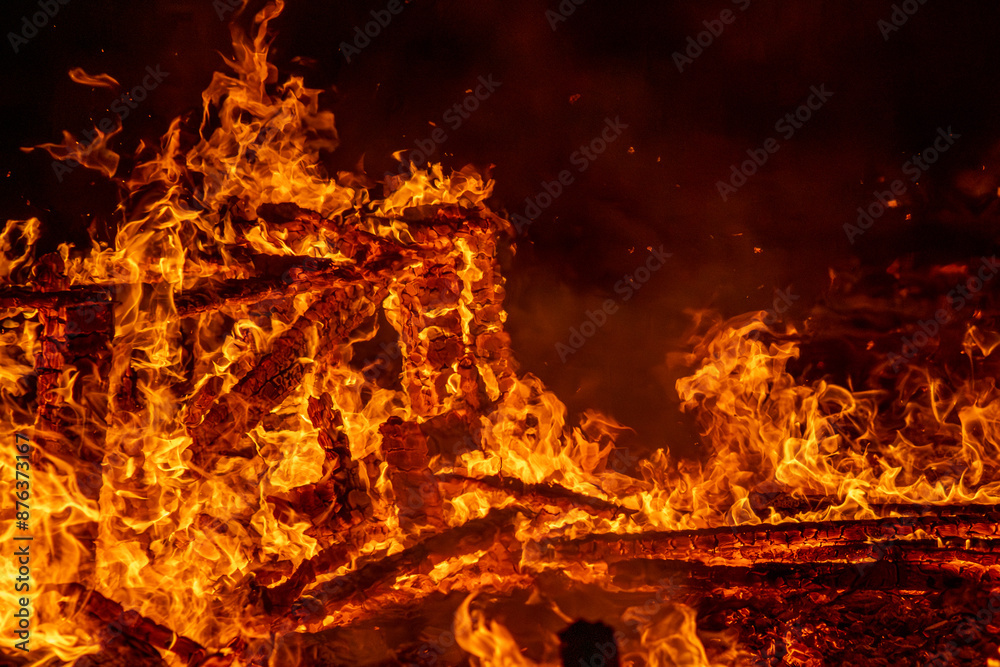 A dramatic image of a fierce fire burning intensely against the dark night sky. The bright orange and yellow flames highlight the raw energy and destructive power of the blaze. Copy space available. A dramatic image of a fierce fire burning intensely against the dark night sky. The bright orange and yellow flames highlight the raw energy and destructive power of the blaze. Copy space available.