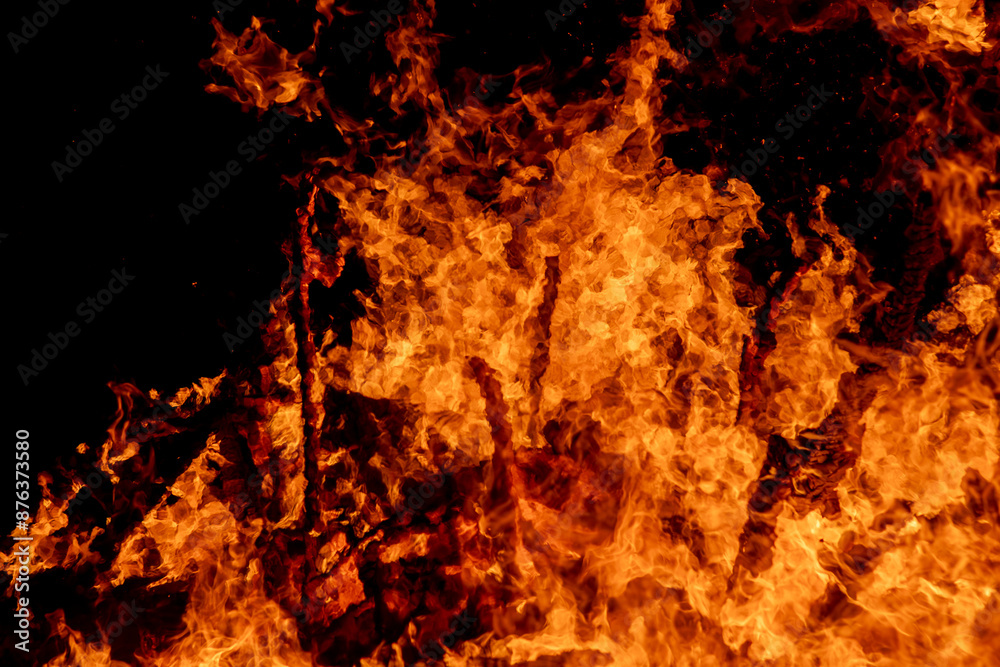 Obraz premium A dramatic image of a fierce fire burning intensely against the dark night sky. The bright orange and yellow flames highlight the raw energy and destructive power of the blaze. Copy space available.