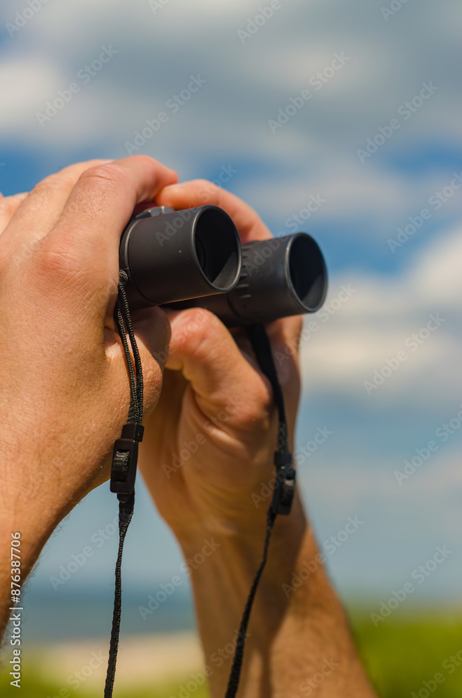 Male hand are holding binoculars on the beach. High quality photo Male hand are holding binoculars on the beach. High quality photo