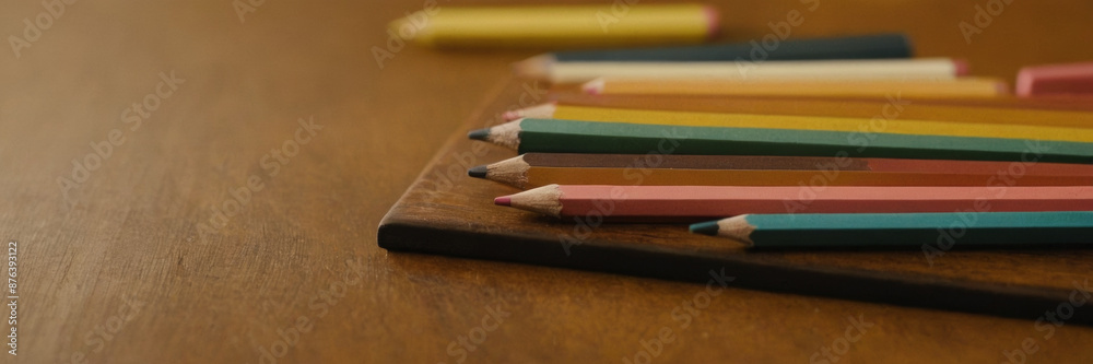 stack of freshly sharpened pencils, colorful erasers, and rulers neatly arranged on a wooden desk.