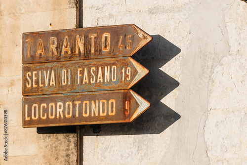 Old vintage signs or directions towards Taranto, Selva di Fasano and Locorotondo, bigger cities in puglia region of southern italy. Rusty signboard.