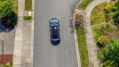 Title: Aerial view of a gray car driving through a suburban neighborhood arriving at home; drone follow shot