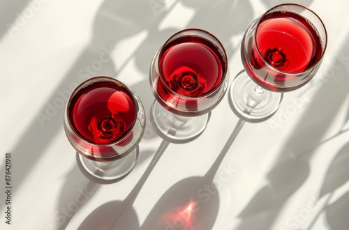 Two Glasses of Red Wine With Leaf Shadows on a White Surface