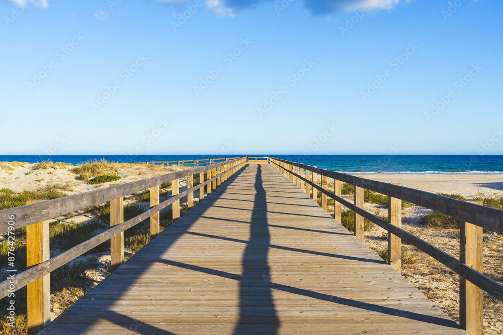 Sand dunes at sunset and a long wooden boardwalk leading to the beach Sand dunes at sunset and a long wooden boardwalk leading to the beach