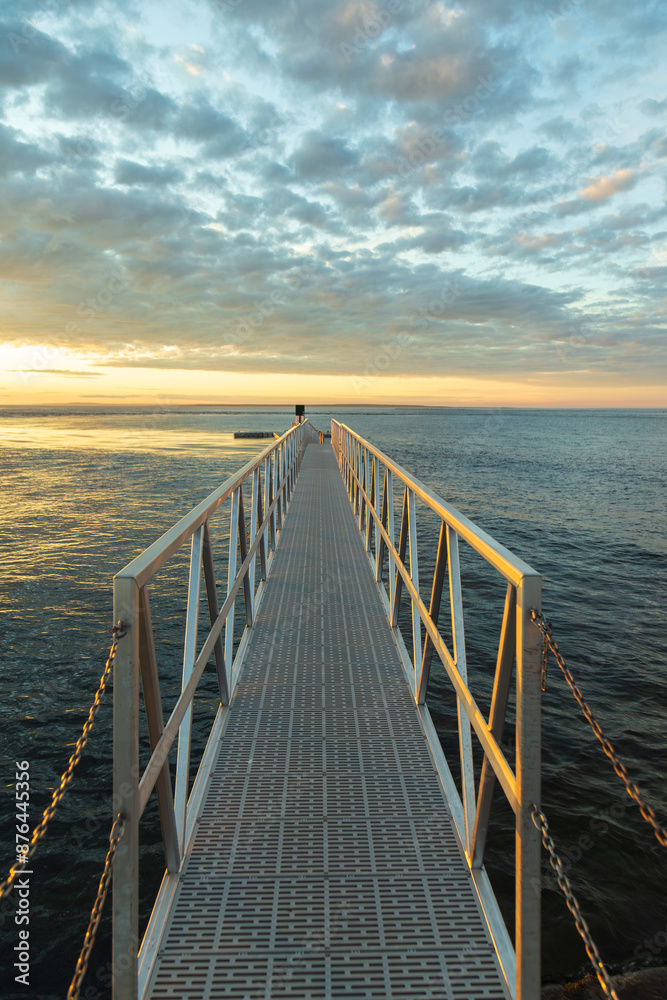 Fototapeta premium Vertical view of metallic walkway leading to wharf at sunrise on the Île aux Perroquets (Parrots Island) in the Mingan Archipelago National Park Reserve, Quebec, Canada