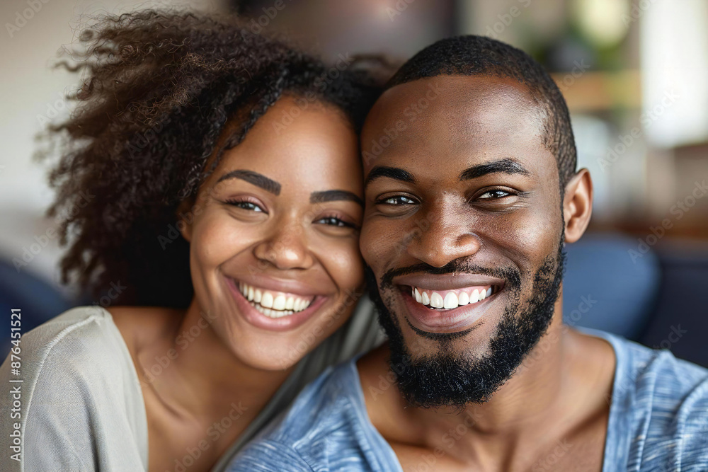 Beautiful African American couple smiling and laughing while watching television at home, the man with a well-groomed beard. Beautiful African American couple smiling and laughing while watching television at home, the man with a well-groomed beard.