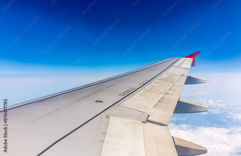 Fototapeta premium View from the airplane window at a beautiful cloudy sky and the airplane wing