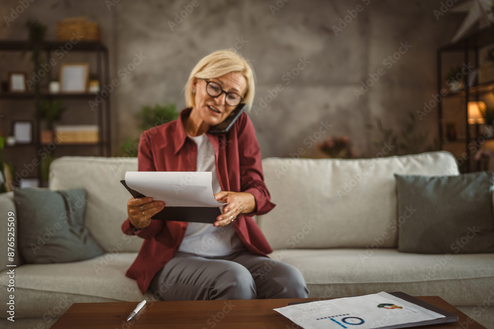 Mature senior woman work from home on clipboard and talk on cellphone Mature senior woman work from home on clipboard and talk on cellphone