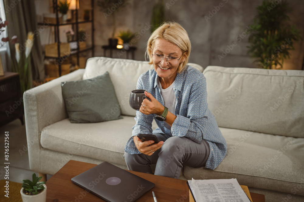 Obraz premium Mature woman work from home and use mobile phone on break drink coffee