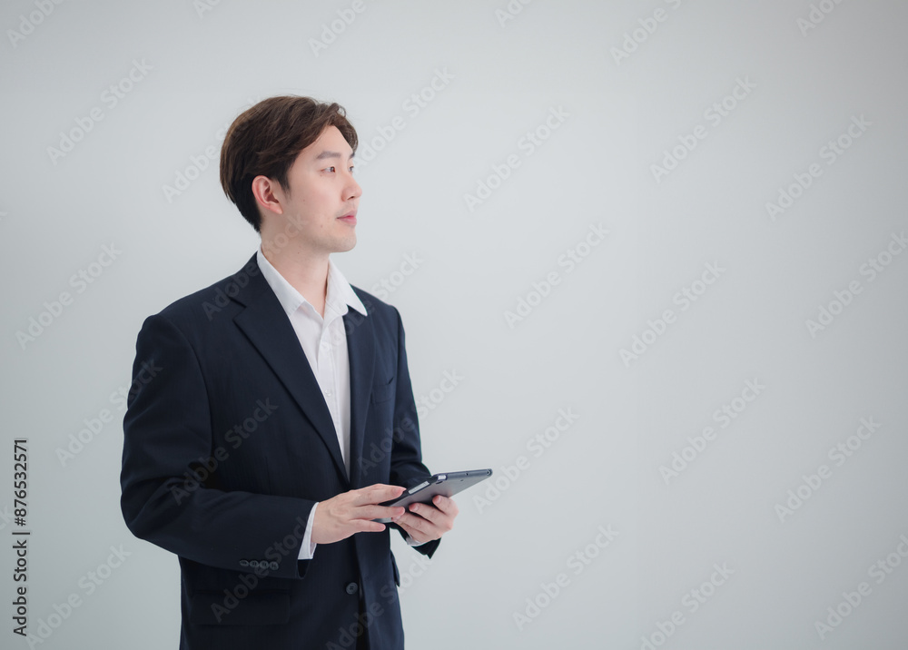 Business man portrait asian one person wearing black suit handsome standing looking success committed hand holding computer and notebook ready for work in room office company, with white background Business man portrait asian one person wearing black suit handsome standing looking success committed hand holding computer and notebook ready for work in room office company, with white background