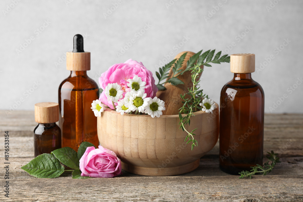 Aromatherapy. Different essential oils, flowers, mortar and pestle on wooden table Aromatherapy. Different essential oils, flowers, mortar and pestle on wooden table