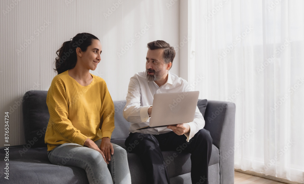 Business caucasian with latin woman two pason sit on sofa talk giving advice and think analyze look and hand holding insurance, investment and financial computer agreement in room living office. Business caucasian with latin woman two pason sit on sofa talk giving advice and think analyze look and hand holding insurance, investment and financial computer agreement in room living office.