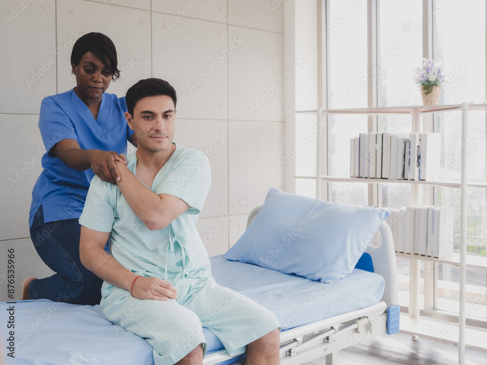 Patient caucasian man with woman nurse black people carer physical therapist two person sit patient bed talk help support give advice and holding relax massage on arm body inside room hospital clinic. Patient caucasian man with woman nurse black people carer physical therapist two person sit patient bed talk help support give advice and holding relax massage on arm body inside room hospital clinic.