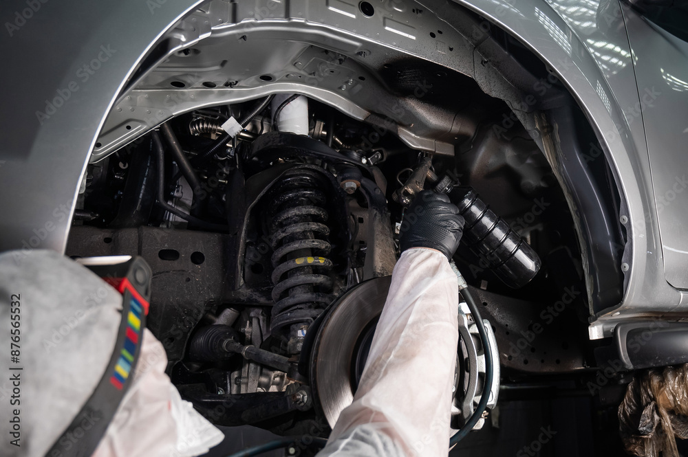 An auto mechanic applies anti-corrosion mastic to the underbody of a car. An auto mechanic applies anti-corrosion mastic to the underbody of a car.