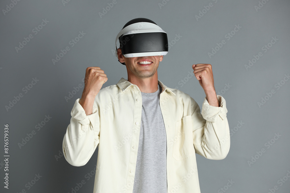 Smiling man using virtual reality headset on gray background Smiling man using virtual reality headset on gray background