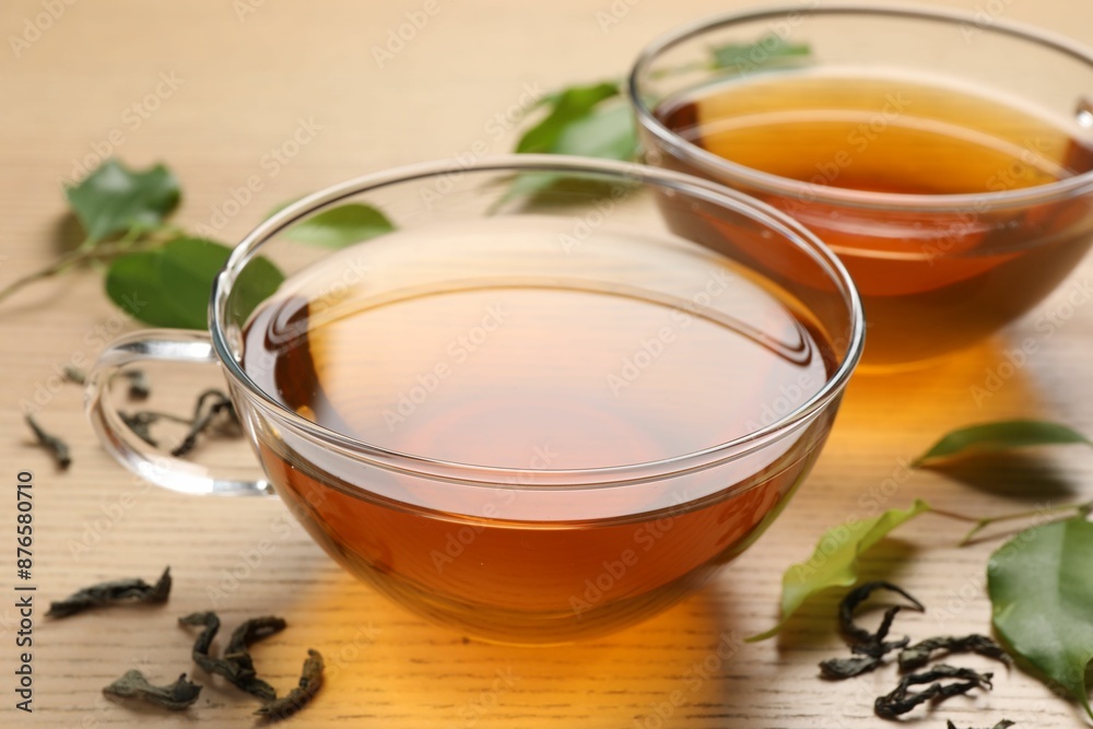 Refreshing green tea in cups and leaves on wooden table, closeup Refreshing green tea in cups and leaves on wooden table, closeup