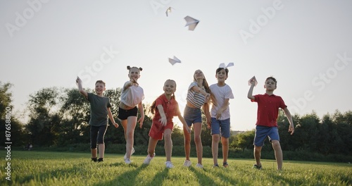 Group of Children Tossing Paper Airplanes in the Park at Dusk, Embracing Summer Fun, Slow Motion