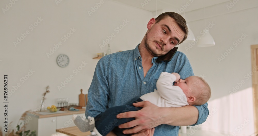 Obraz premium Multitasking Dad Balancing Work Call with Holding Adorable Son at Home